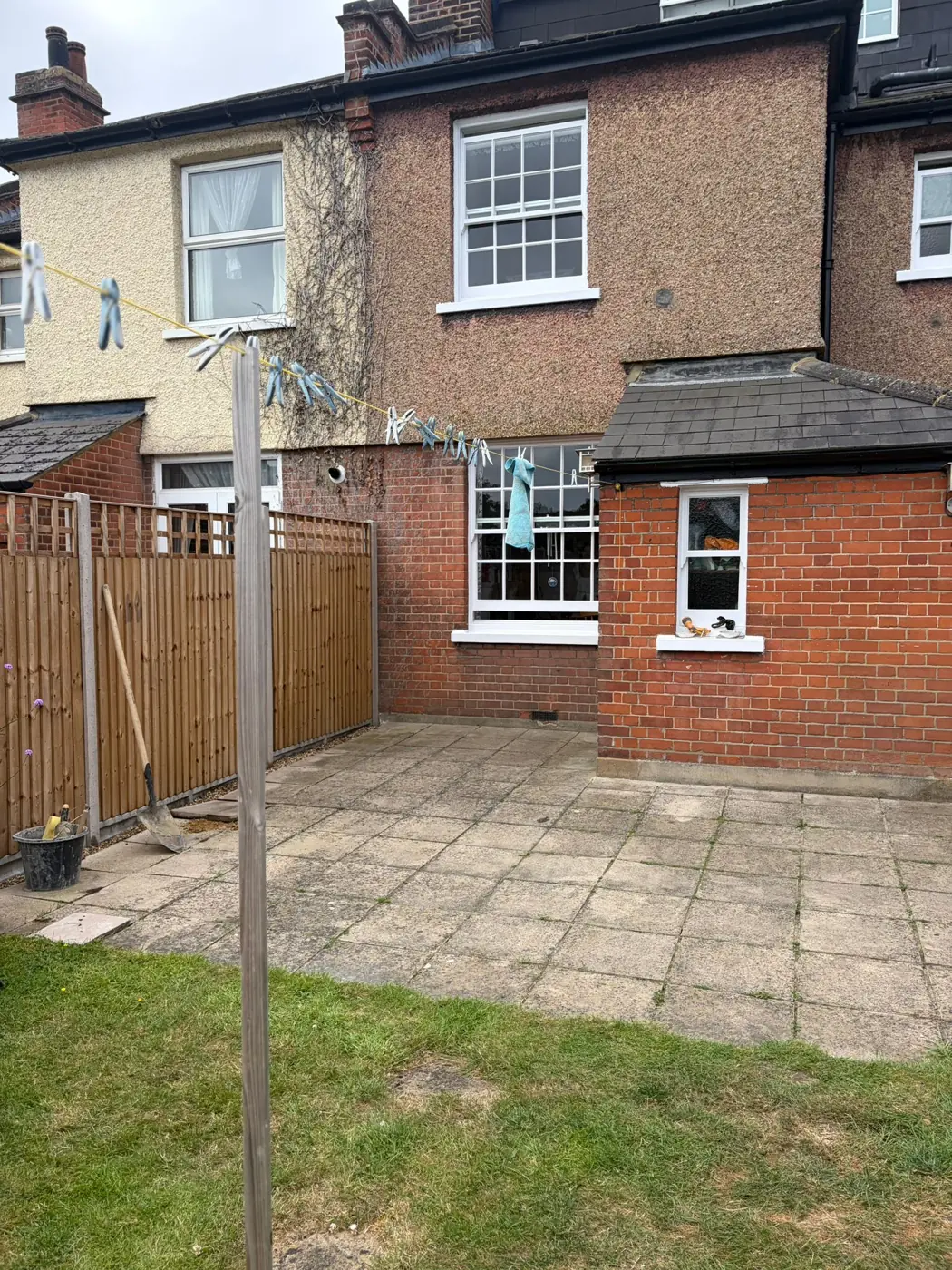 Older square patio slabs outside a brick house