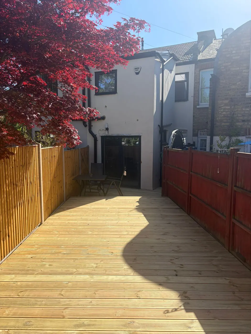 Timber decking running through a narrow fenced side garden